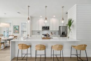 a kitchen with white cabinets and a island with bar stools at 248 Beach Bike Way in Inlet Beach