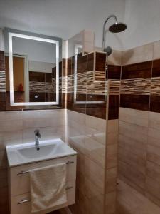 y baño con lavabo y ducha con espejo. en Sétány apartman en Mórahalom