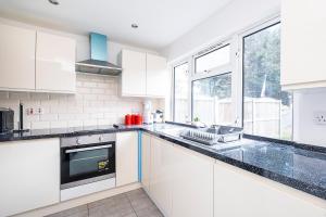 a kitchen with white cabinets and black counter tops at Dagenham Self catering House for Larger Groups with Free Parking in Dagenham +38 photos
