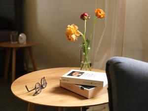 una mesa con un jarrón de flores y un libro y vasos en Soltau Apartments en Herford