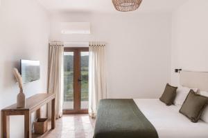 a white bedroom with a bed and a window at Quinta do Freixo in Benafim