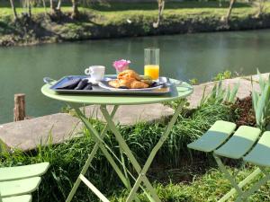 a table with a plate of food on it next to a river at La Belle Epoque - Chambres d'hôtes & SPA in Damvix