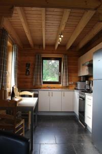 eine Küche mit weißen Schränken, einem Tisch und einem Fenster in der Unterkunft Bouleau in Vresse-sur-Semois