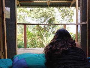 Una mujer tumbada en una cama mirando por una ventana en Monte La MaMa Ecolodge, en Viotá