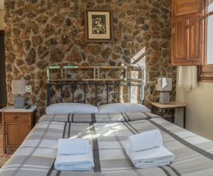 a bedroom with a bed and a stone wall at Hotel Rural Fuente La Teja in Güéjar-Sierra +71 photos