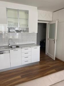 cocina con armarios blancos y suelo de madera en Iva Apartment Split, en Split