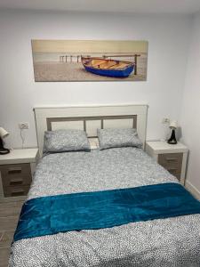 a bedroom with a bed and a painting of a boat at Beach House Tajao in La Jaca