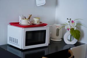 un four micro-ondes sur une table avec un vase et des fleurs dans l'établissement Hôtel Le Bellevue, à Tarascon-sur-Ariège