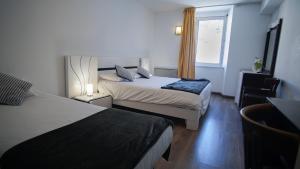 a hotel room with two beds and a window at Hôtel Le Bellevue in Tarascon-sur-Ariège