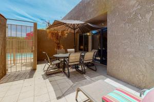 a patio with a table and chairs and an umbrella at Caballeros Condo in Palm Springs