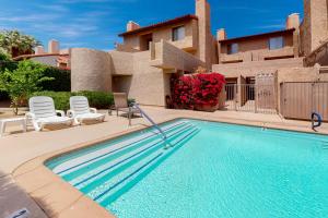 a swimming pool with two chairs and a house at Caballeros Condo in Palm Springs