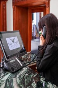 a woman talking on a cell phone next to a laptop computer at Hotel Epidamn Boutique & Spa in Durrës