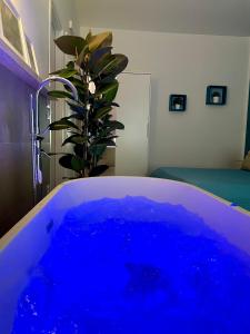 una grande vasca blu in una stanza con una pianta di Le Coq Suites a Roma