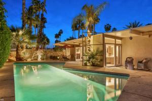 una piscina di fronte a una casa con palme di Casa Tranquillo a Palm Springs