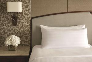 a white bed with a white comforter and pillows at Shangri-La Jakarta in Jakarta