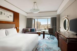 a hotel room with a bed and a desk with a computer at Shangri-La Qingdao - May Fourth Square in Qingdao