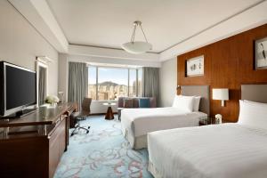a hotel room with two beds and a flat screen tv at Shangri-La Qingdao - May Fourth Square in Qingdao