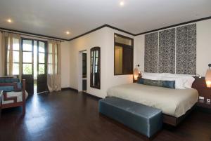 a bedroom with a king sized bed and a couch at The Apsara Rive Droite in Luang Prabang