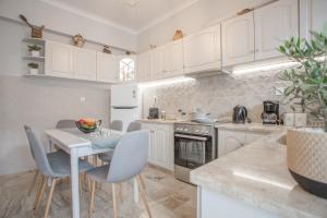 a kitchen with white cabinets and a table and chairs at Onirion Homes : Stella's Home in Kolymvari