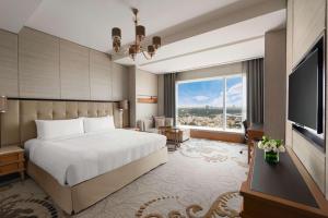 バンガロールにあるシャングリラ ホテル バンガロールのベッドと大きな窓が備わるホテルルームです。