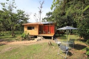 Casa pequeña con mesa, sillas y sombrilla en Mindo Eco Suite con Rio y Cascada en Mindo