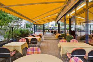 ein Restaurant mit Tischen, Stühlen und gelben Sonnenschirmen in der Unterkunft Good Night Inn in Brig