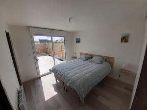 - une chambre avec un lit et une porte coulissante en verre dans l'établissement Villa le Nid Des Dunes & Spa 2 gîtes écologiques, à Santec
