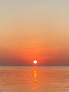 a sunset over the ocean with the sun reflecting in the water at Masirah Beach camp in Al Qārin