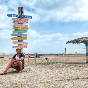 Al QārinにあるMasirah Beach campの浜辺の看板前に座る女