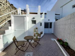a patio with chairs and a table and a building at Cozy Beach House in Ribeira Grande
