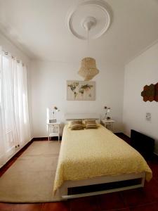 a white bedroom with a bed with a yellow blanket at Cozy Beach House in Ribeira Grande