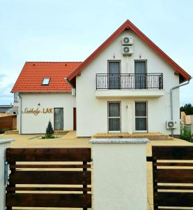 una casa blanca con una valla de madera delante de ella en Székely-Lak Apartman Hegykő en Hegykő