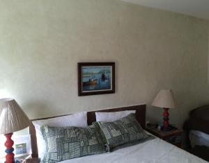 um quarto com uma cama com dois candeeiros e uma imagem na parede em Pousada das Garças em Saquarema