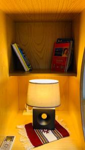 a table with a lamp and books on a shelf at Central Comfy Apartment in Tirana