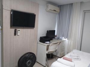 a hotel room with a desk and a television on a wall at Quarto TRIPLO CONFORTAVEL E AMPLO NO BAIRRO DO ESPINHEIRO em RECIFE in Recife