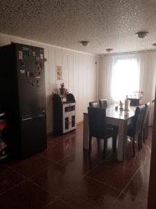 een eetkamer met een tafel en een koelkast bij Гостевой дом Поти in Poti