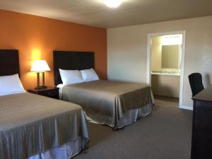 a hotel room with two beds and a mirror at Downtown Motel Woodward in Woodward