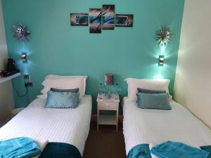 two beds in a room with a blue wall at The Star and Garter Hotel in Linlithgow