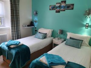 two beds in a room with a blue wall at The Star and Garter Hotel in Linlithgow