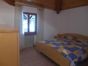 een slaapkamer met een bed en een raam bij La Mansarda di nonna Delfa in Pinzolo