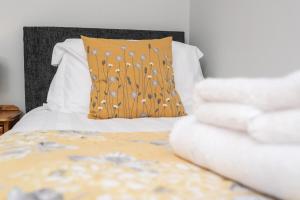 uma cama com uma almofada castanha e lençóis brancos em Merlin House em Cockfield