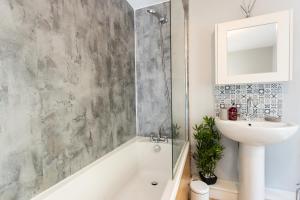 a bathroom with a shower and a sink and a tub at Merlin House in Cockfield