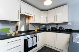 a kitchen with white cabinets and black counter tops at Merlin House in Cockfield