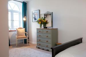 a bedroom with a dresser and a mirror and a chair at The Old Chapel Leyburn in Leyburn