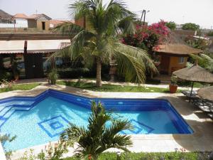 una piscina en un patio con una palmera en Le Dakan, en Saly Portudal