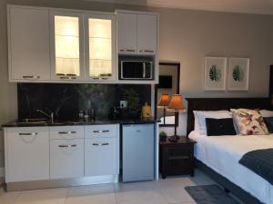 a kitchen with white cabinets and a bed in a room at Brewer Place in Port Elizabeth