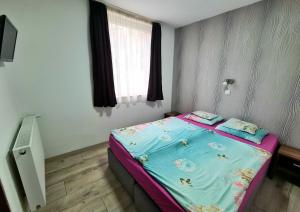 Dormitorio pequeño con cama con sábanas azules y ventana en Marika Apartman Sopron, en Sopron