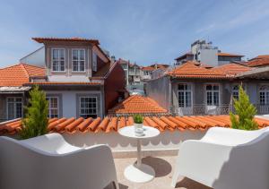 un patio con sillas blancas, una mesa y edificios en BO - Almada en Oporto