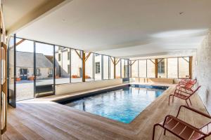 a pool in a house with chairs and windows at Manoir du Guern in Pluvigner