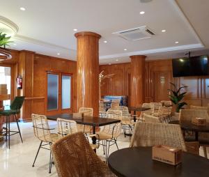 a dining room with tables and chairs and a television at Hotel Teremar in Benidorm